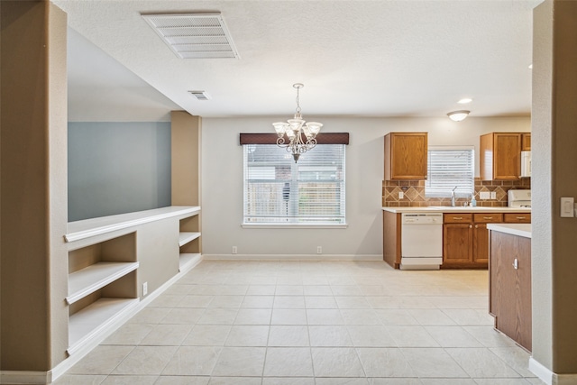 kitchen with sink, an inviting chandelier, white dishwasher, decorative light fixtures, and decorative backsplash