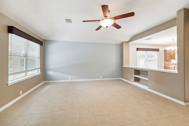 tiled spare room featuring ceiling fan with notable chandelier and vaulted ceiling