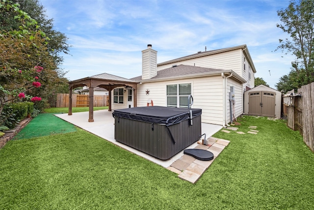 back of property featuring a gazebo, a lawn, a hot tub, and a storage unit