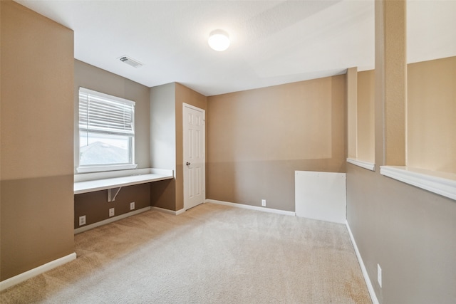 carpeted spare room with built in desk