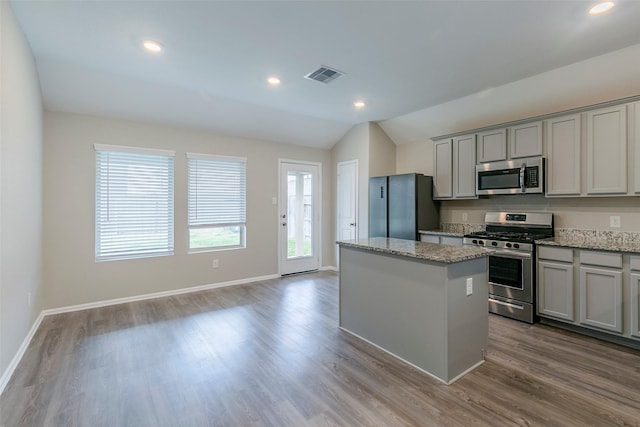 kitchen with hardwood / wood-style floors, gray cabinetry, stainless steel appliances, and a kitchen island