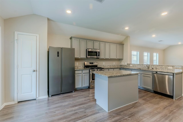 kitchen featuring light wood-type flooring, vaulted ceiling, stainless steel appliances, and a center island