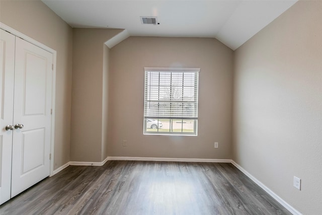 empty room with vaulted ceiling and dark hardwood / wood-style flooring