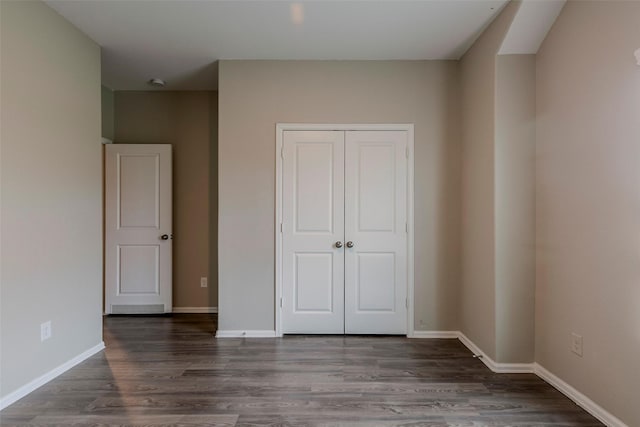 unfurnished bedroom featuring a closet and dark hardwood / wood-style flooring