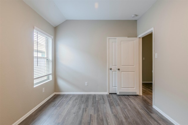 spare room featuring vaulted ceiling and hardwood / wood-style flooring