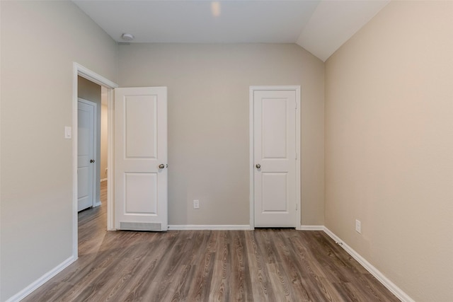 unfurnished bedroom featuring lofted ceiling and dark hardwood / wood-style flooring