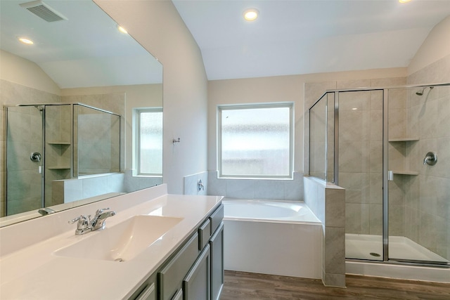 bathroom with vaulted ceiling, independent shower and bath, hardwood / wood-style floors, and vanity