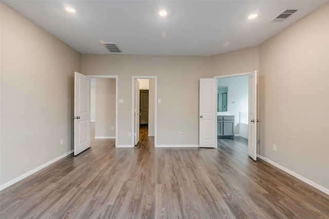 unfurnished bedroom featuring ensuite bath and light wood-type flooring