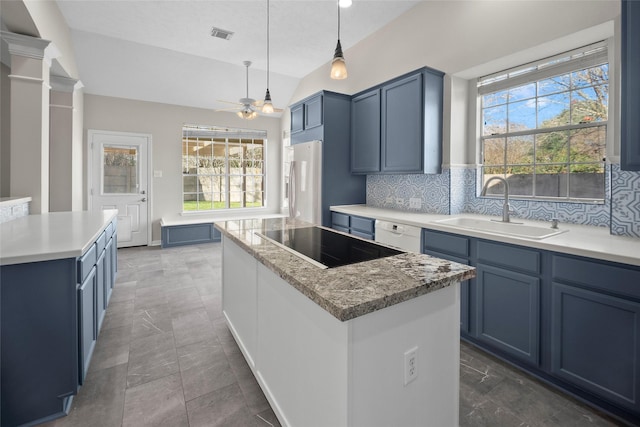 kitchen with backsplash, a center island, sink, and stainless steel refrigerator