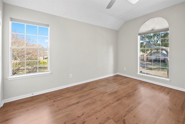 empty room with hardwood / wood-style floors, ceiling fan, a healthy amount of sunlight, and vaulted ceiling