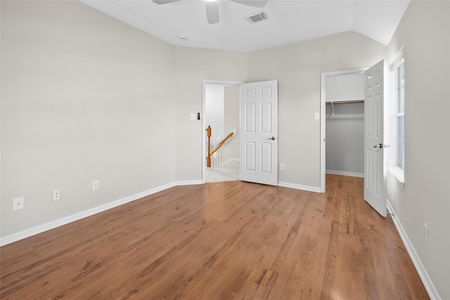 unfurnished bedroom with a spacious closet, ceiling fan, light hardwood / wood-style flooring, multiple windows, and a closet