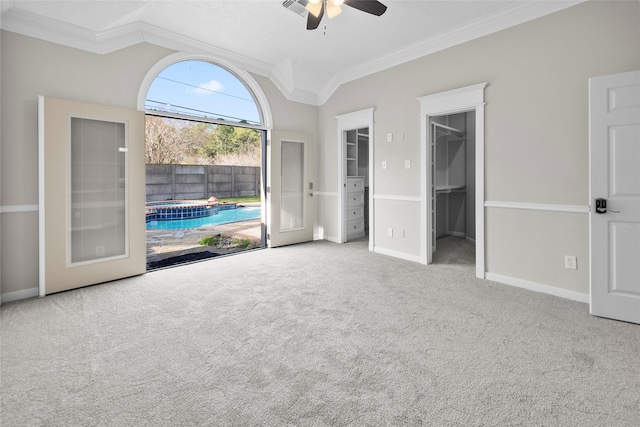 unfurnished bedroom featuring carpet, french doors, crown molding, ceiling fan, and a spacious closet