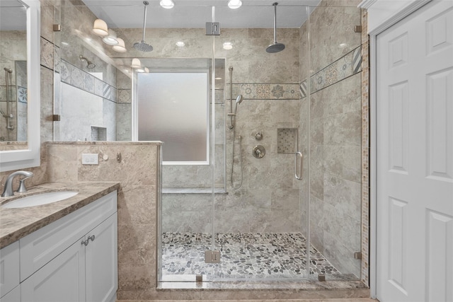 bathroom with walk in shower, vanity, and tile walls