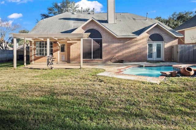 back of property featuring french doors, a patio, a fenced in pool, and a lawn