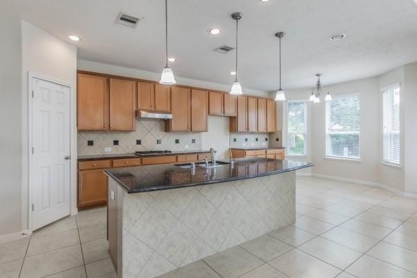 kitchen with a notable chandelier, light tile patterned flooring, sink, and a kitchen island with sink