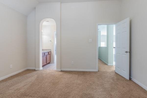 carpeted spare room with lofted ceiling