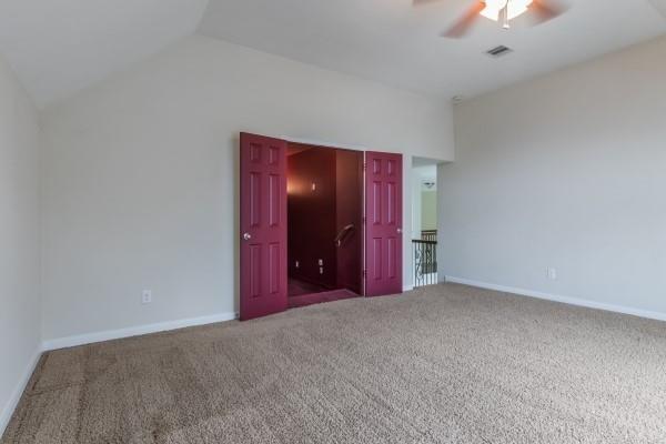 unfurnished bedroom with carpet, vaulted ceiling, and ceiling fan