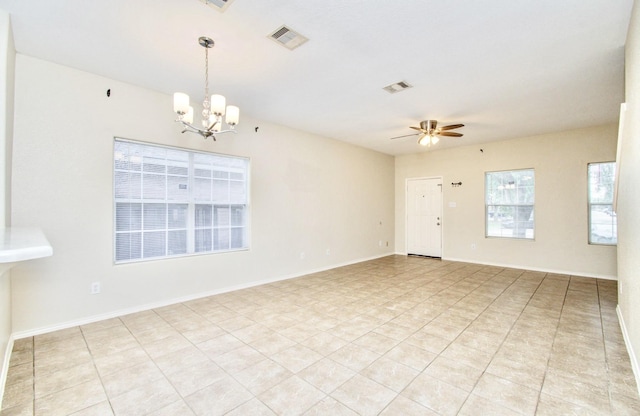 tiled spare room featuring ceiling fan with notable chandelier