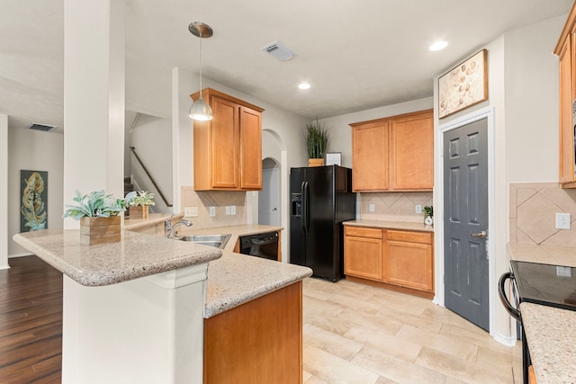 kitchen featuring sink, light stone counters, kitchen peninsula, decorative backsplash, and black appliances