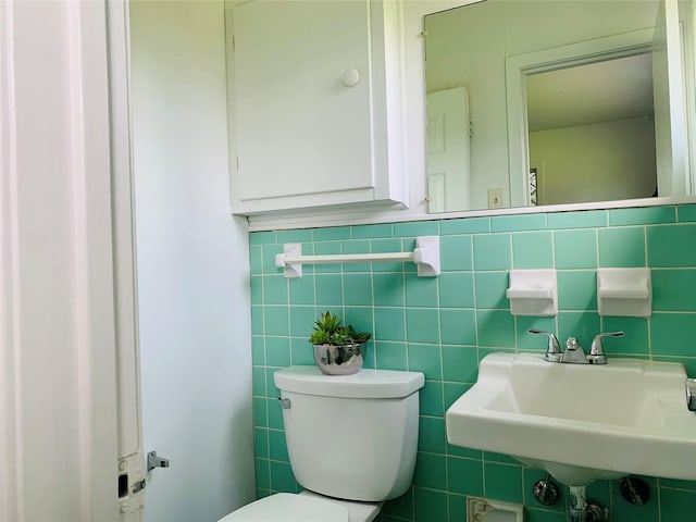 bathroom with sink, tile walls, and toilet