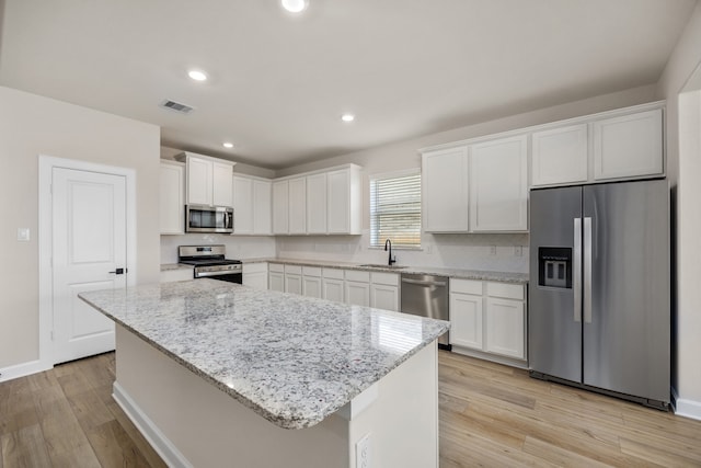 kitchen with a center island, sink, white cabinets, and stainless steel appliances