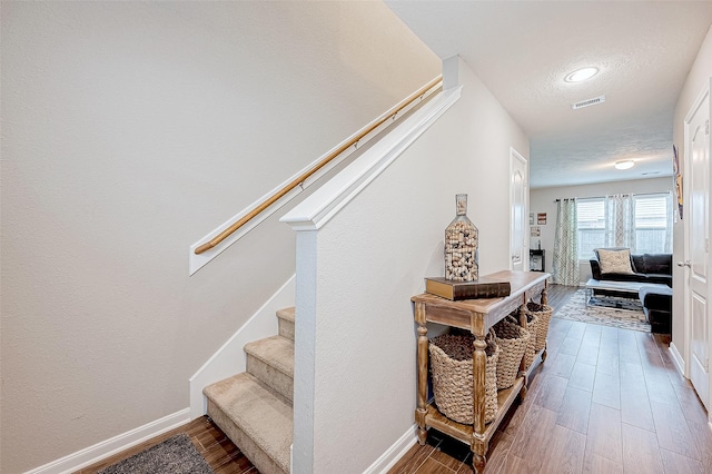 stairway with a textured ceiling and hardwood / wood-style flooring