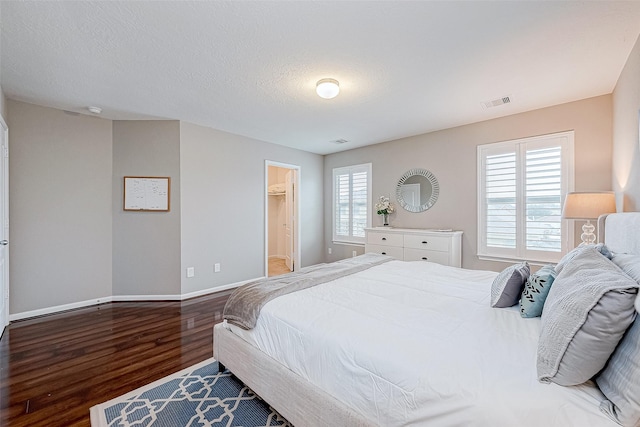 bedroom featuring hardwood / wood-style floors, a textured ceiling, and multiple windows