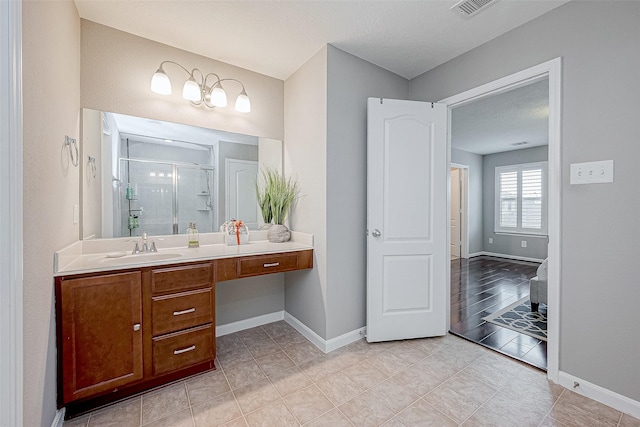 bathroom with tile patterned flooring, vanity, a shower with shower door, and a textured ceiling