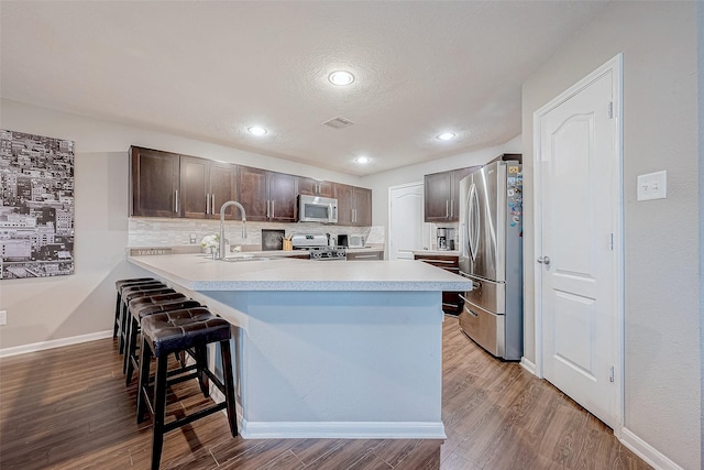 kitchen featuring sink, decorative backsplash, appliances with stainless steel finishes, kitchen peninsula, and a breakfast bar area