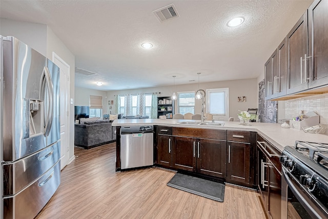 kitchen with pendant lighting, decorative backsplash, kitchen peninsula, and stainless steel appliances