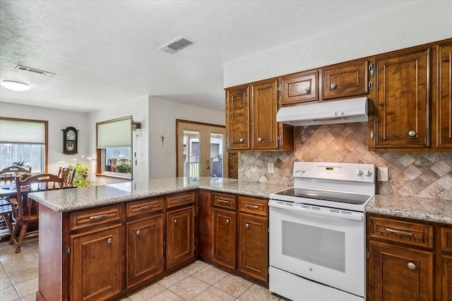 kitchen with electric range, decorative backsplash, kitchen peninsula, and a wealth of natural light