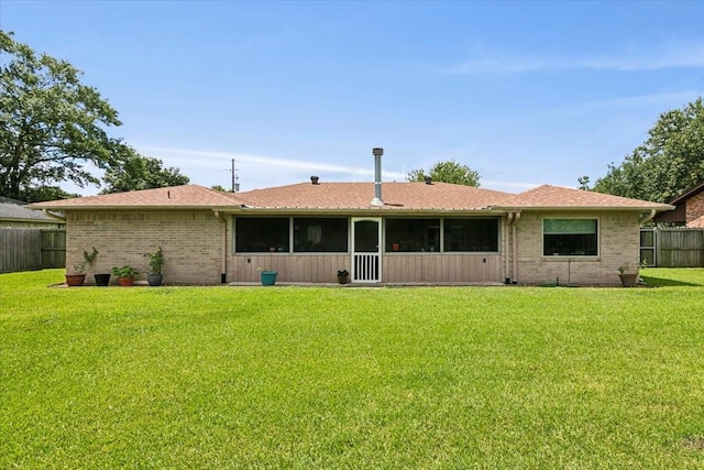 rear view of house featuring a lawn and a sunroom