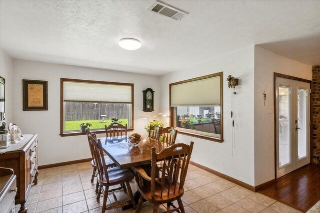 tiled dining area with a textured ceiling and a healthy amount of sunlight