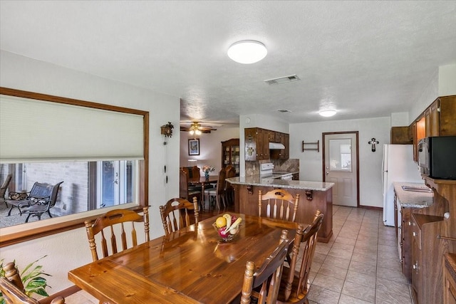 dining area with light tile patterned floors, a textured ceiling, and ceiling fan