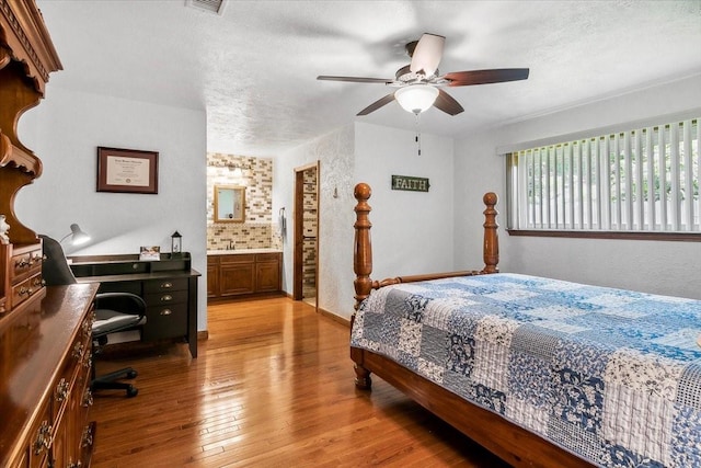 bedroom with a textured ceiling, connected bathroom, light hardwood / wood-style floors, and ceiling fan