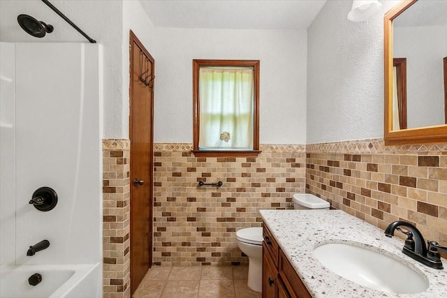 full bathroom featuring shower / bathtub combination, vanity, toilet, and tile walls