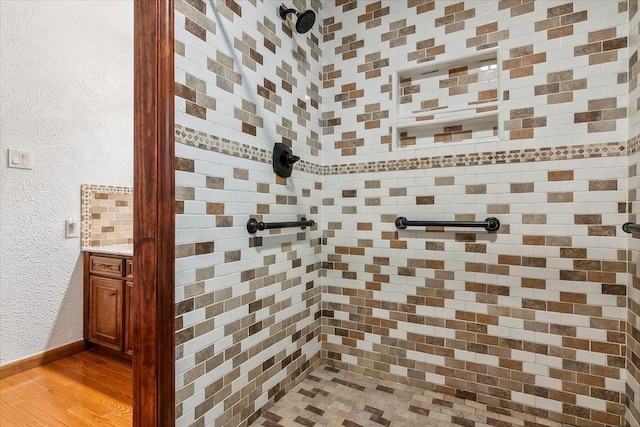 bathroom featuring vanity, wood-type flooring, and tiled shower