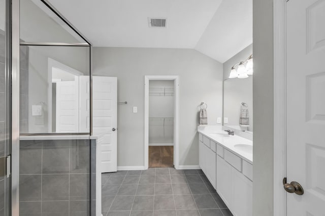 bathroom featuring tile patterned floors, vanity, lofted ceiling, and walk in shower