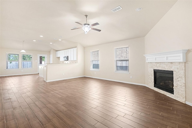 unfurnished living room featuring ceiling fan, lofted ceiling, a fireplace, and dark wood-type flooring