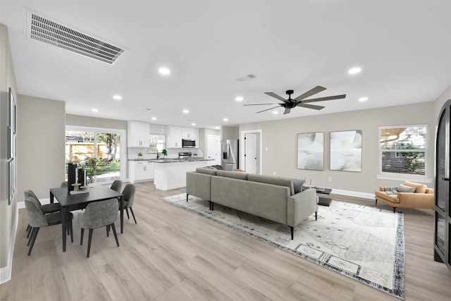 living room with ceiling fan and light hardwood / wood-style flooring