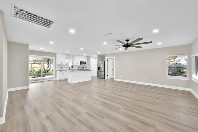 unfurnished living room with ceiling fan, light wood-type flooring, and sink