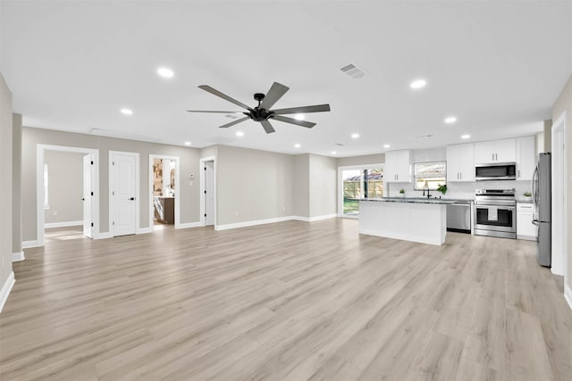 unfurnished living room featuring ceiling fan, sink, and light hardwood / wood-style flooring