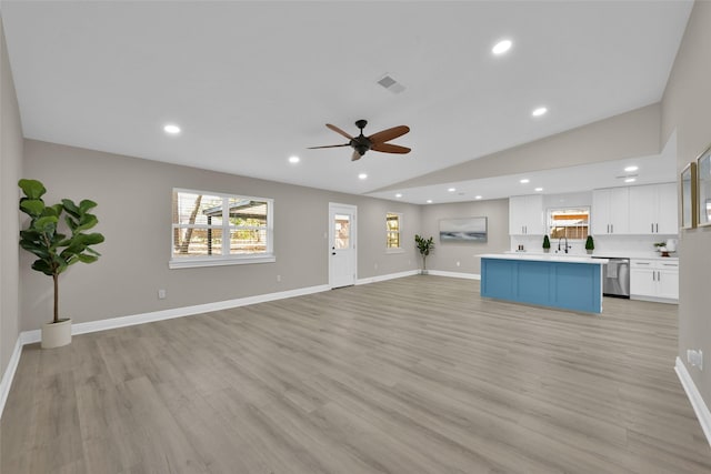 unfurnished living room with light wood-type flooring, vaulted ceiling, ceiling fan, and sink