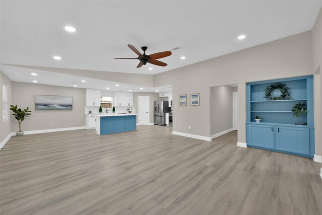 unfurnished living room with ceiling fan, built in features, lofted ceiling, and light hardwood / wood-style flooring