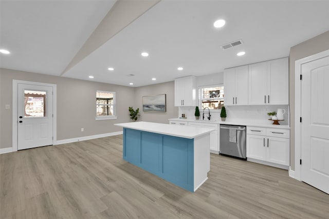 kitchen featuring dishwasher, a center island, sink, white cabinets, and light wood-type flooring