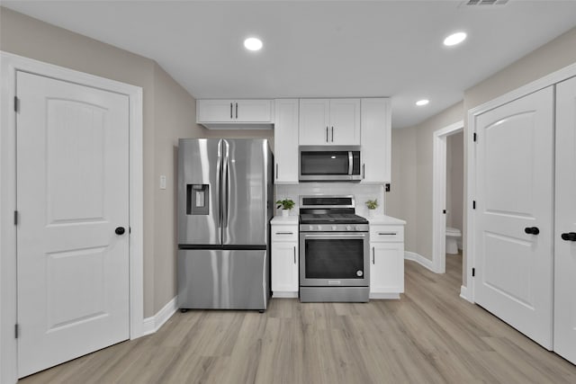 kitchen featuring backsplash, white cabinetry, stainless steel appliances, and light hardwood / wood-style floors