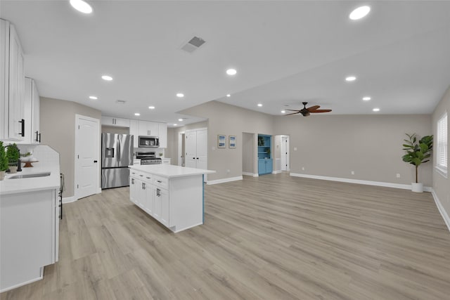 kitchen featuring stainless steel appliances, ceiling fan, sink, white cabinets, and a kitchen island