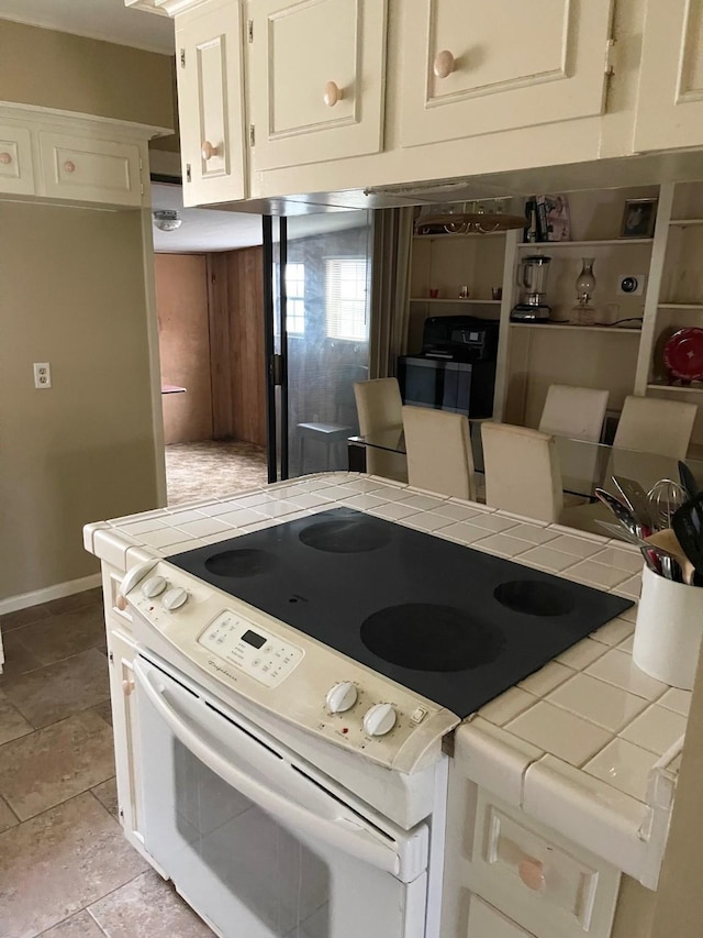 kitchen featuring white range with electric cooktop, tile counters, and light tile patterned floors