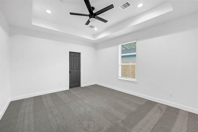 carpeted empty room with a raised ceiling and ceiling fan