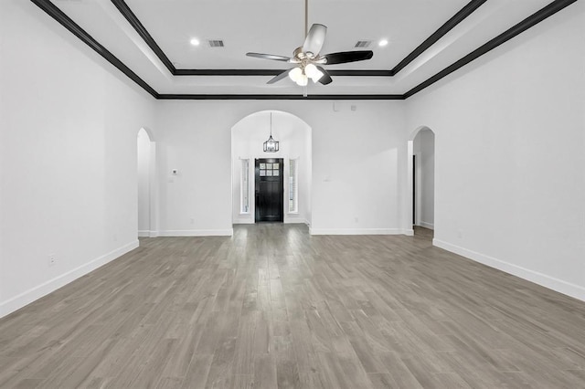 unfurnished living room with a tray ceiling, ceiling fan, and ornamental molding